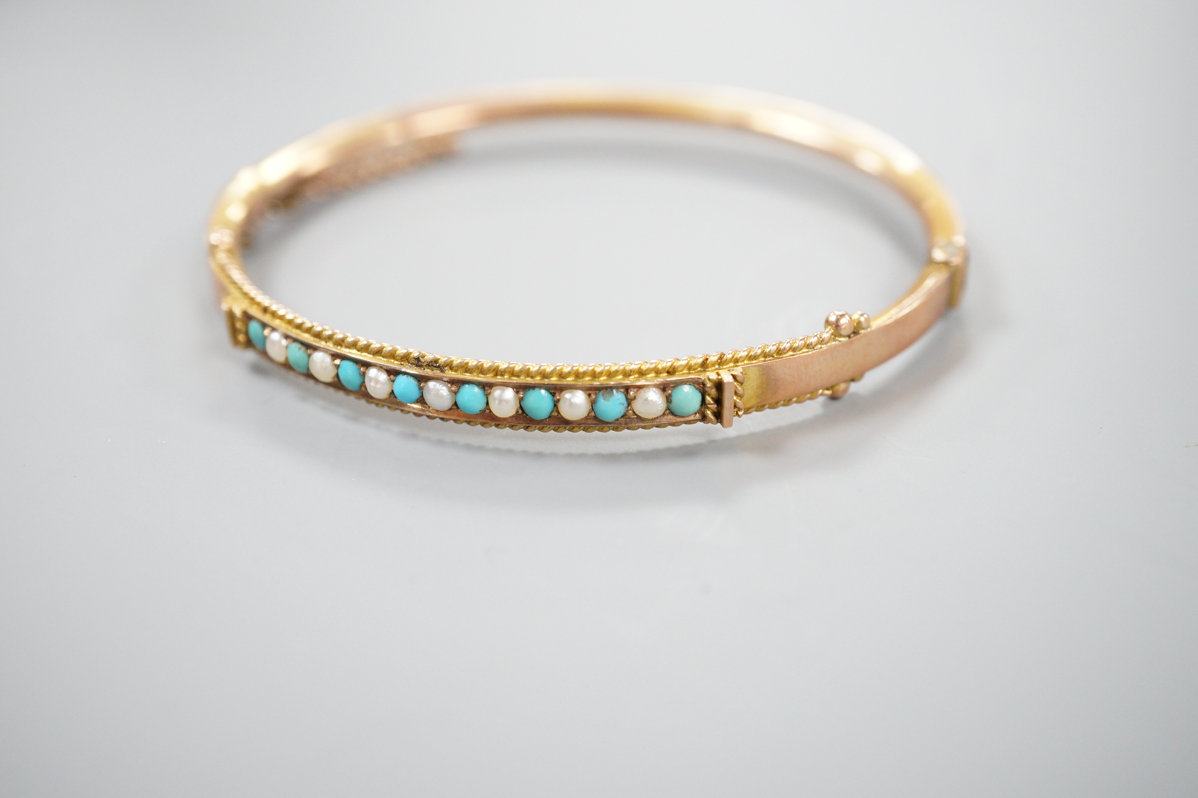 A late Victorian 9ct gold, seed pearl and turquoise set hinged bangle, 58mm, gross weight 6.7 grams.